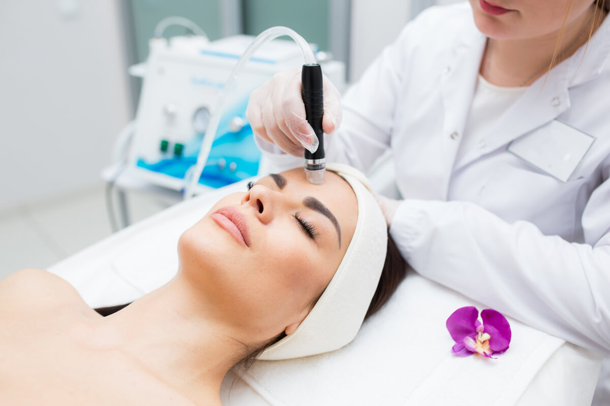 doctor-cosmetologist makes the procedure Microdermabrasion of the facial skin of a beautiful, Exfoliation, Rejuvenation And Hydratation. Cosmetology.