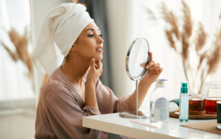 beautiful woman with hair wrapped in a towel looking herself in a mirror at home.